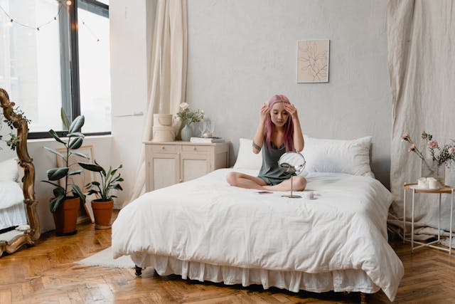 Woman on a bed looking at face in vanity mirror - by Tima Miroshnichenko from Pexels